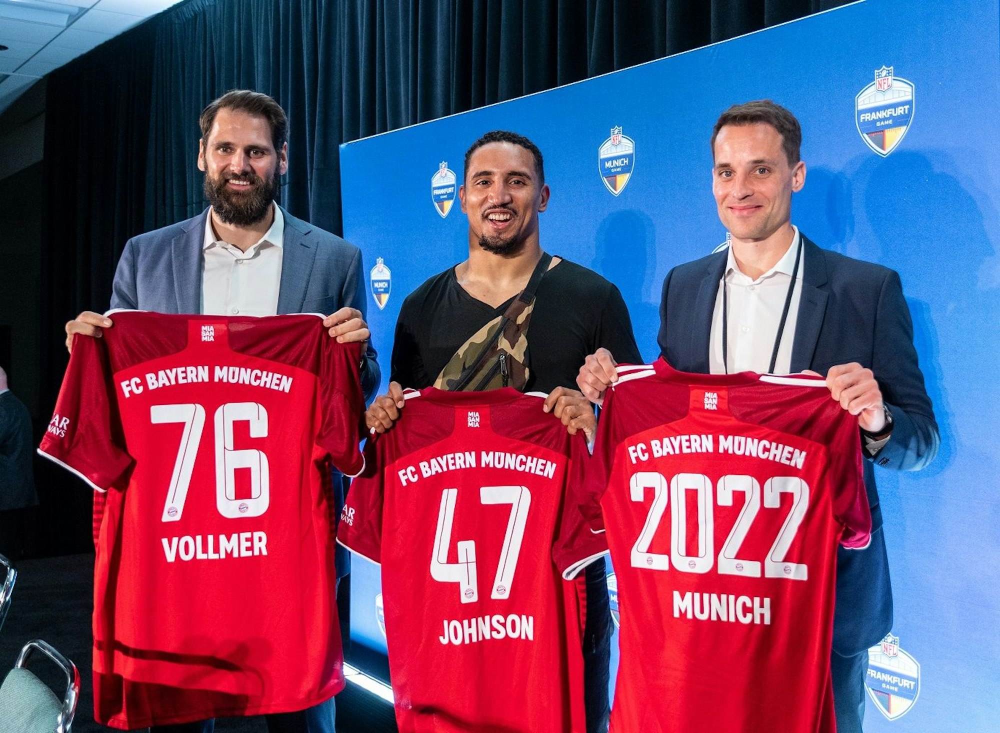 Der ehemalige NFL-Profi Sebastian Vollmer (v.l.), NFL-Profi Jakob Johnson und der NFL-Deutschland-Chef Alexander Steinforth nach einer Pressekonferenz mit Trikots des FC Bayern München in die Kamera.