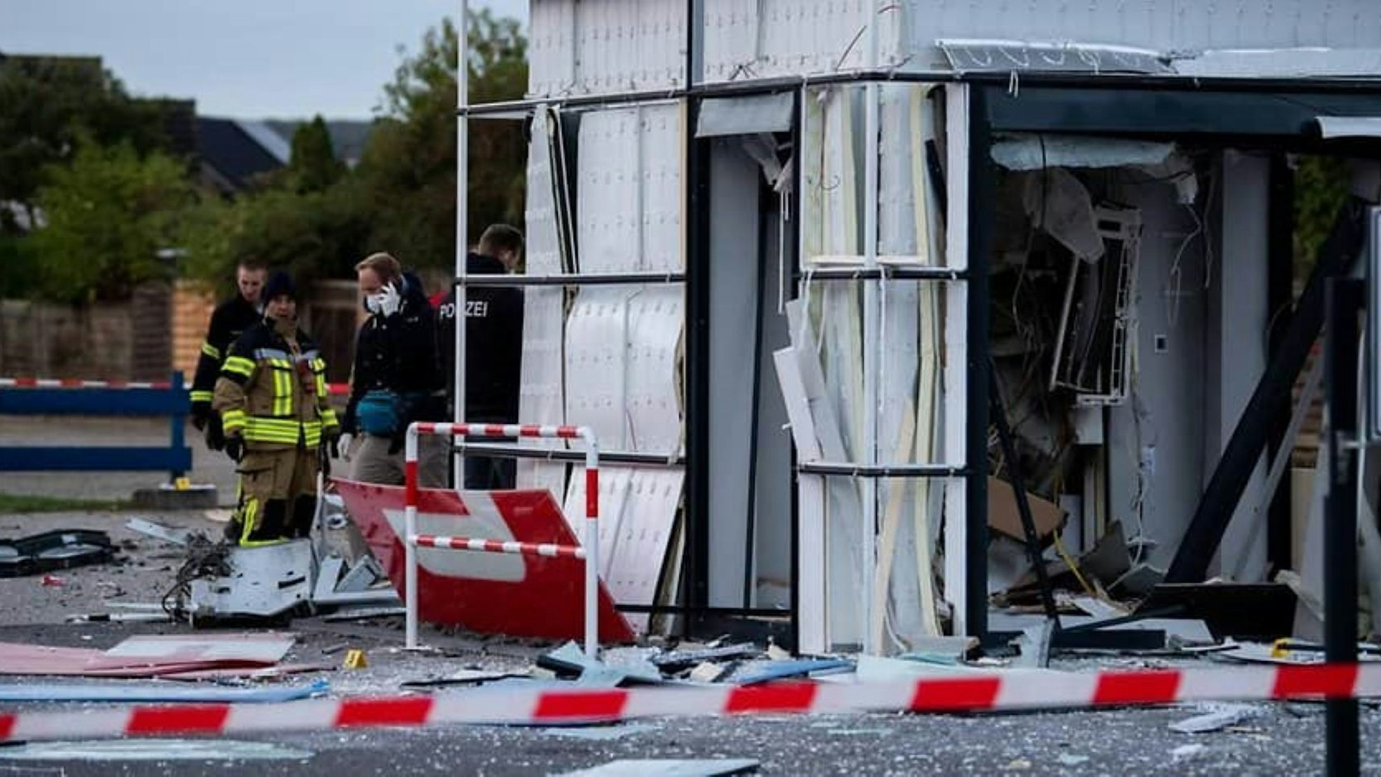 Ein Container, in dem sich ein Geldautomat befand, ist von der Polizei mit Flatterband abgesperrt worden. Überall liegen Trümmerteile.