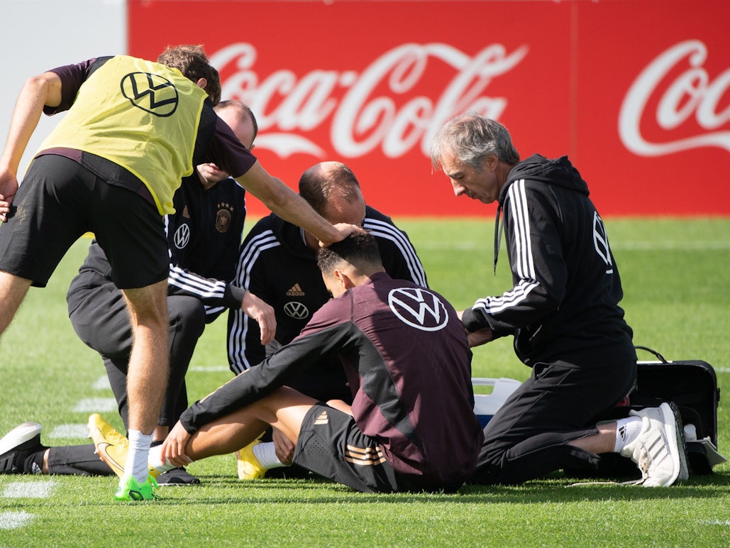 Thomas Müller (l) fasst Jamal Musiala (M) an den Kopf, der von Ärzten betreut wird.