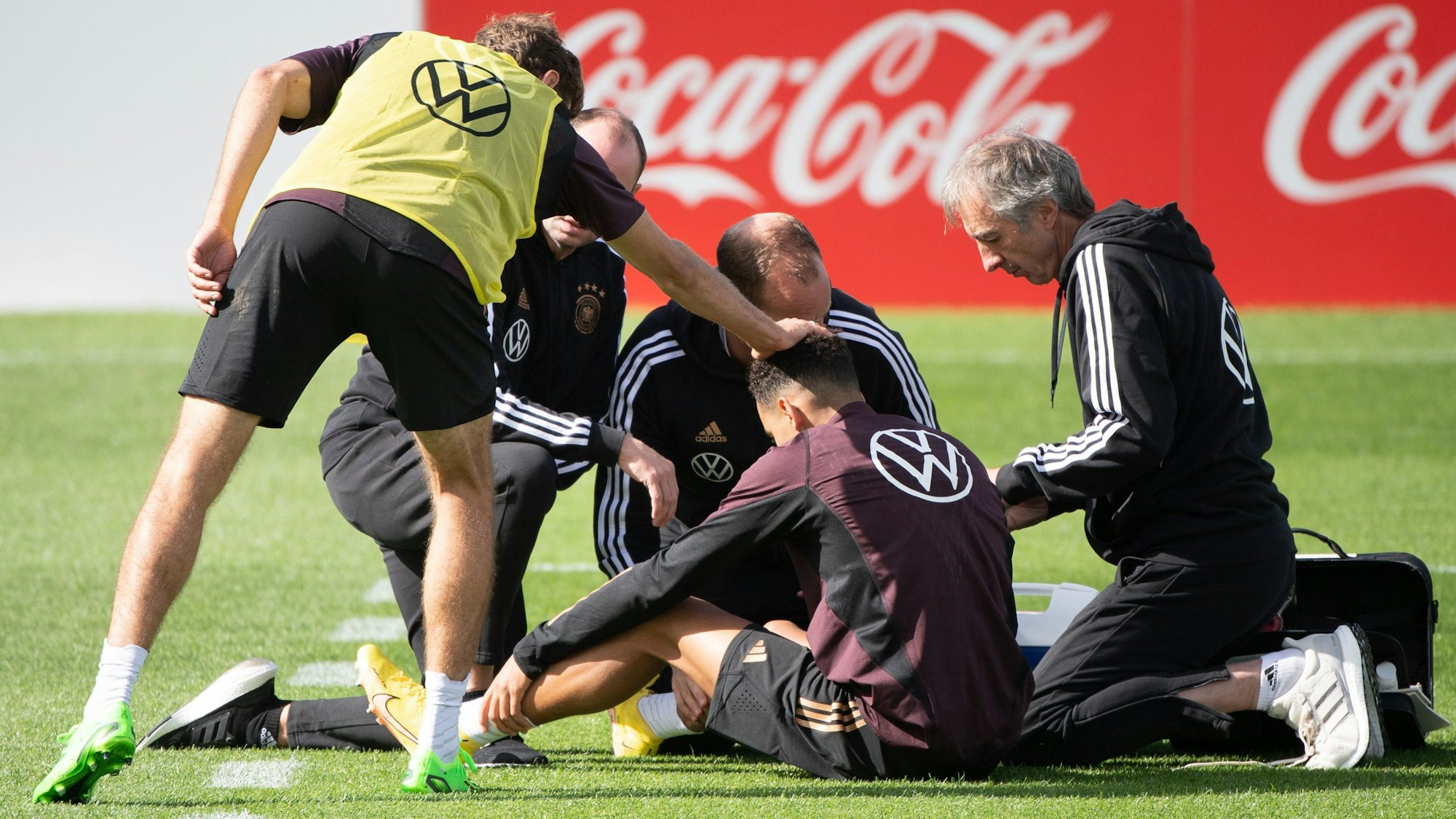Thomas Müller (l) fasst Jamal Musiala (M) an den Kopf, der von Ärzten betreut wird.