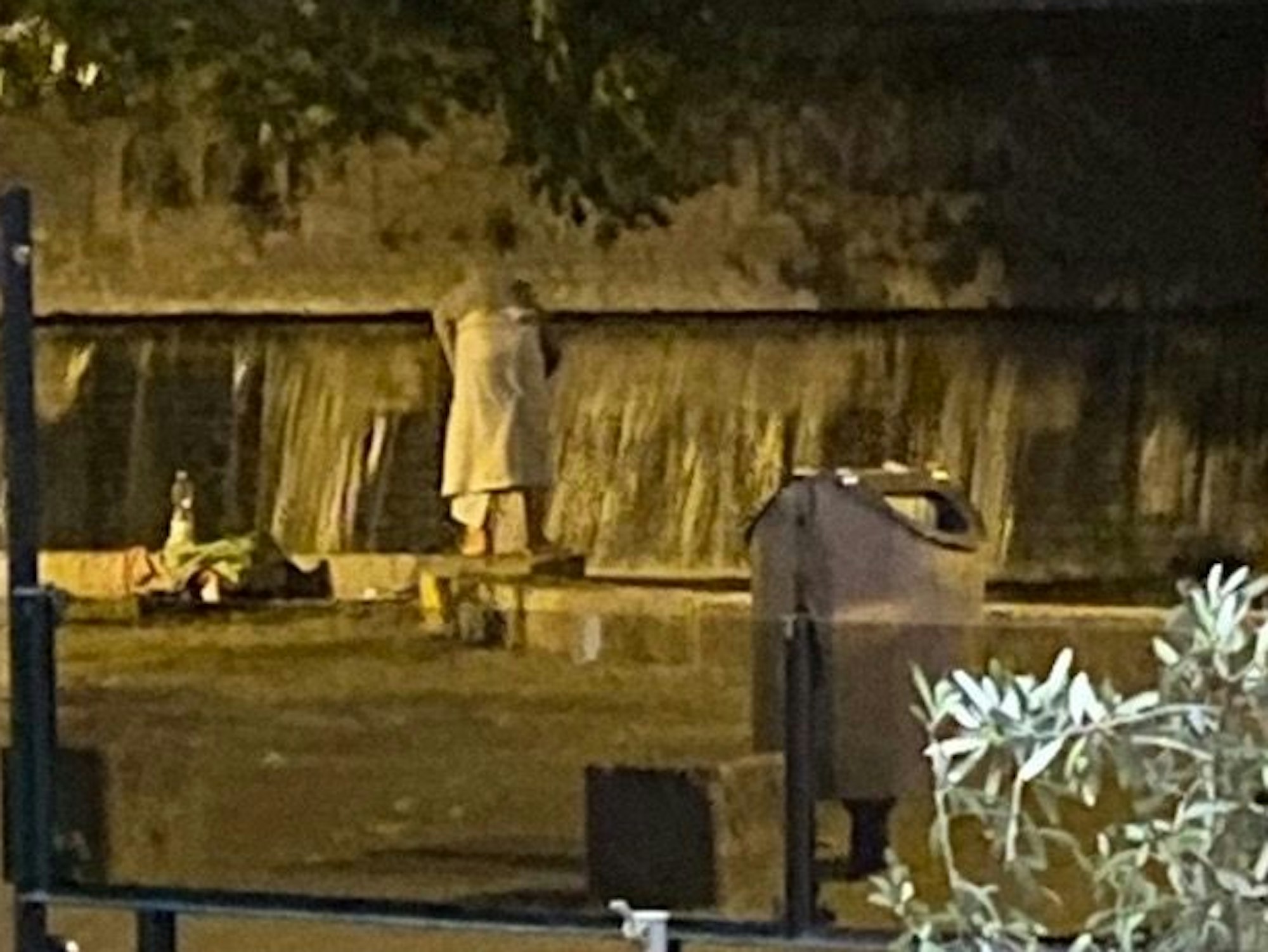 Eine Frau steht neben einem öffentlichen Brunnen mit einem Badetuch.