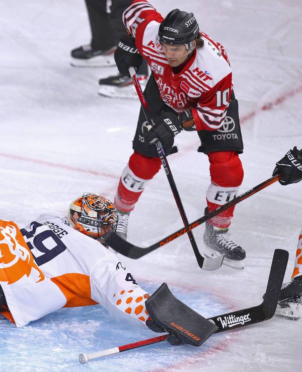 Jon Matsumoto von Kölner Haie schießt den Puck auf das Tor von Justin Pogge, Torhüter von Grizzlys Wolfsburg und trifft zum 1:0 für die Haie.