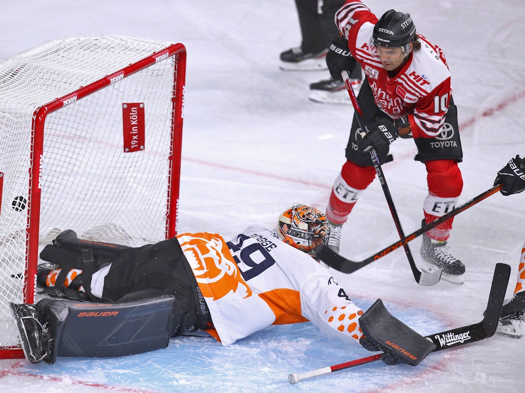Jon Matsumoto von Kölner Haie schießt den Puck auf das Tor von Justin Pogge, Torhüter von Grizzlys Wolfsburg und trifft zum 1:0 für die Haie.