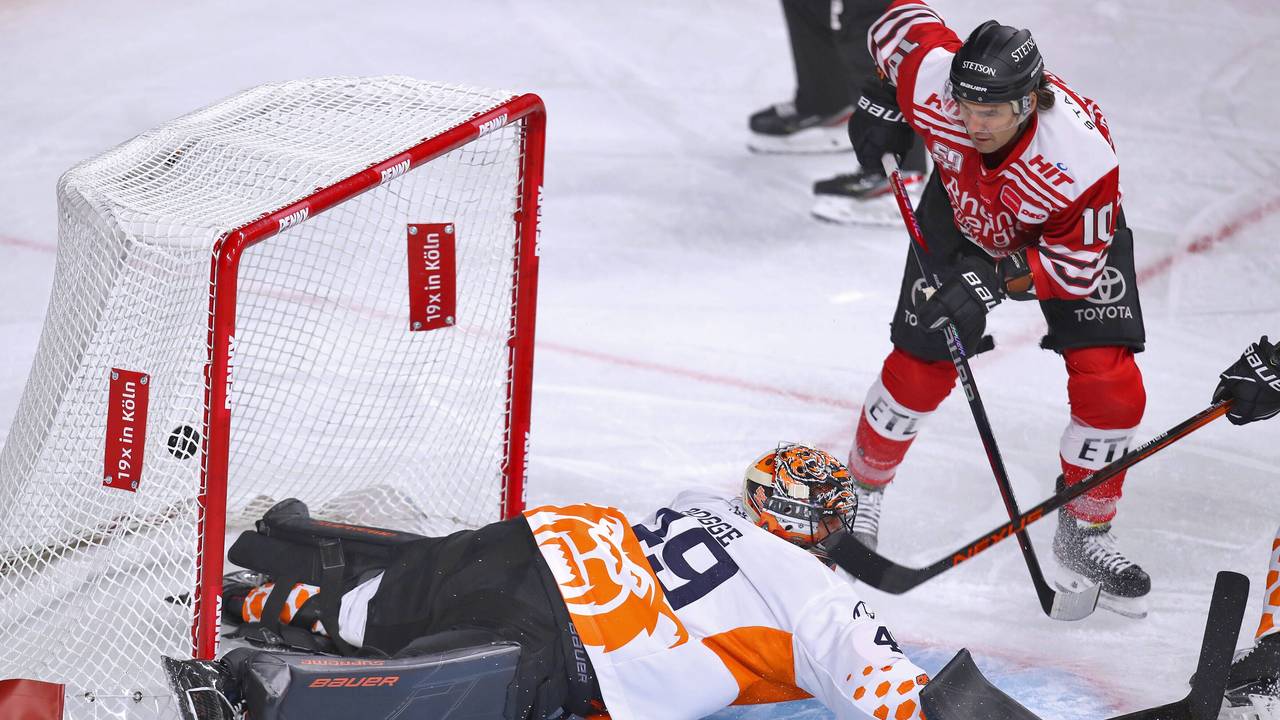 Jon Matsumoto von Kölner Haie schießt den Puck auf das Tor von Justin Pogge, Torhüter von Grizzlys Wolfsburg und trifft zum 1:0 für die Haie.