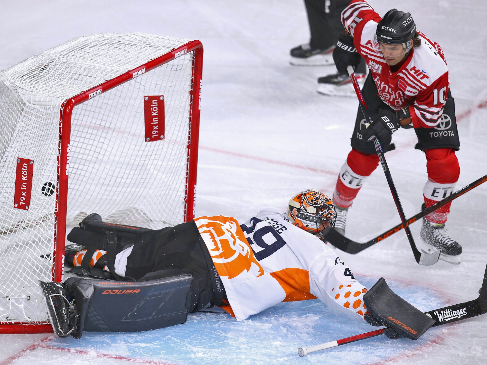 Jon Matsumoto von Kölner Haie schießt den Puck auf das Tor von Justin Pogge, Torhüter von Grizzlys Wolfsburg und trifft zum 1:0 für die Haie.