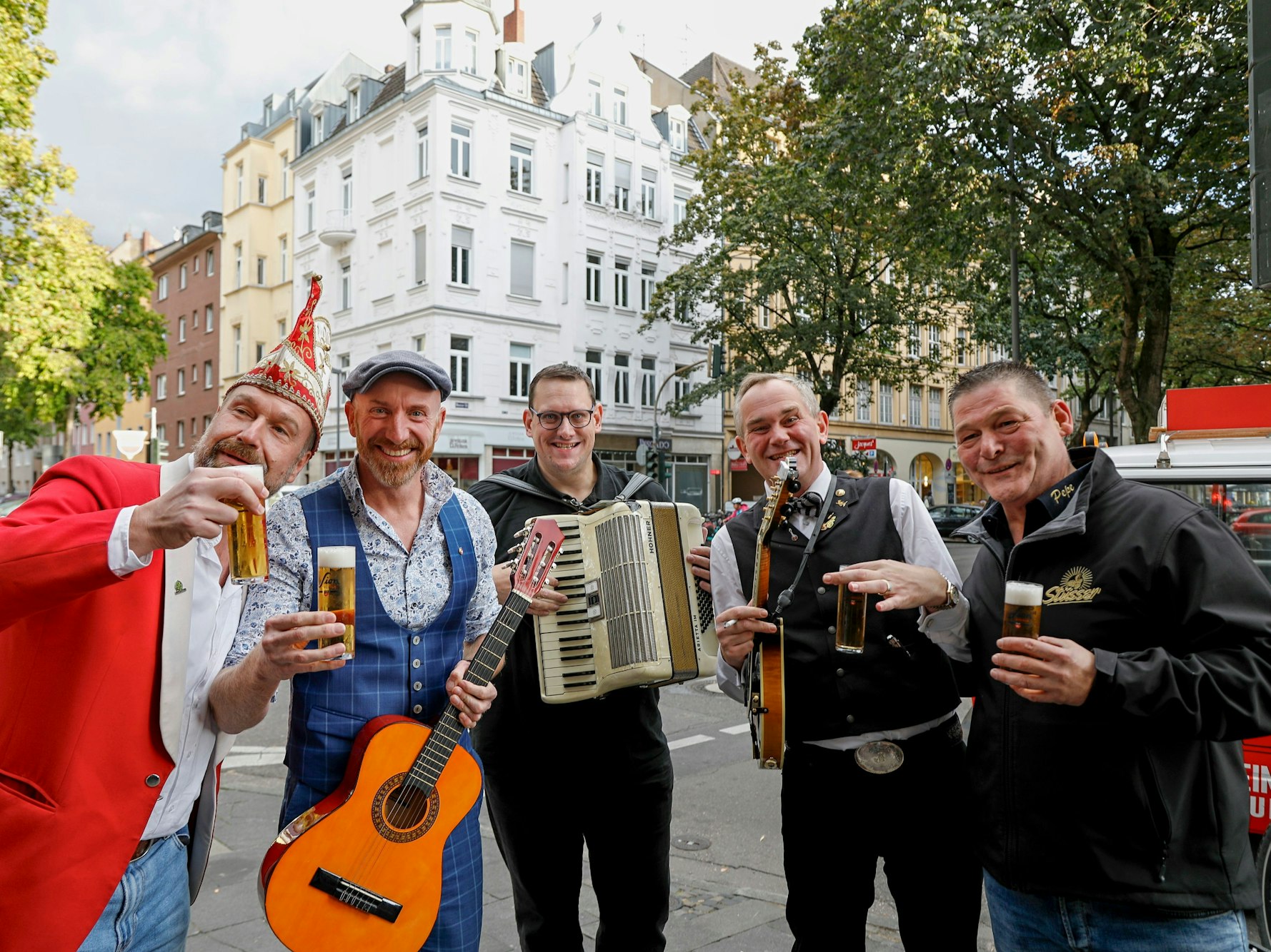 Das Herrengedeck grinst auf der Straße in Köln mit Wirt Peter Stüsser in die Kamera.