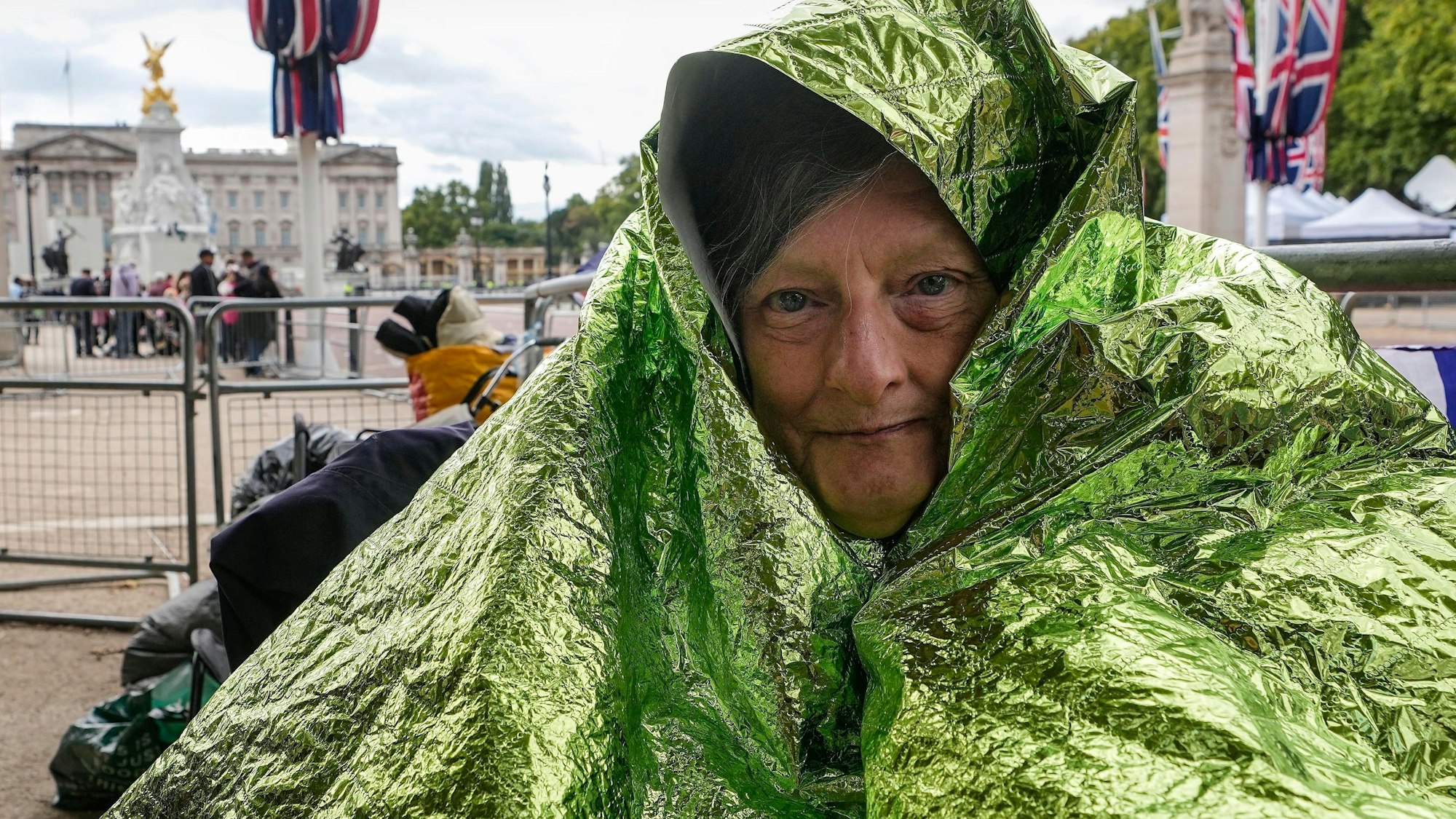Caryll Foster hält sich mit einer Rettungsdecke warm, da sie über Nacht bleiben wird, um in der ersten Reihe bei den Trauerfeierlichkeiten der Königin in der Mall vor dem Buckingham Palace sitzen will.