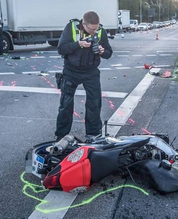Nach einem Unfall in Leverkusen fotografiert ein Polizist das zerstörte Motorrad.