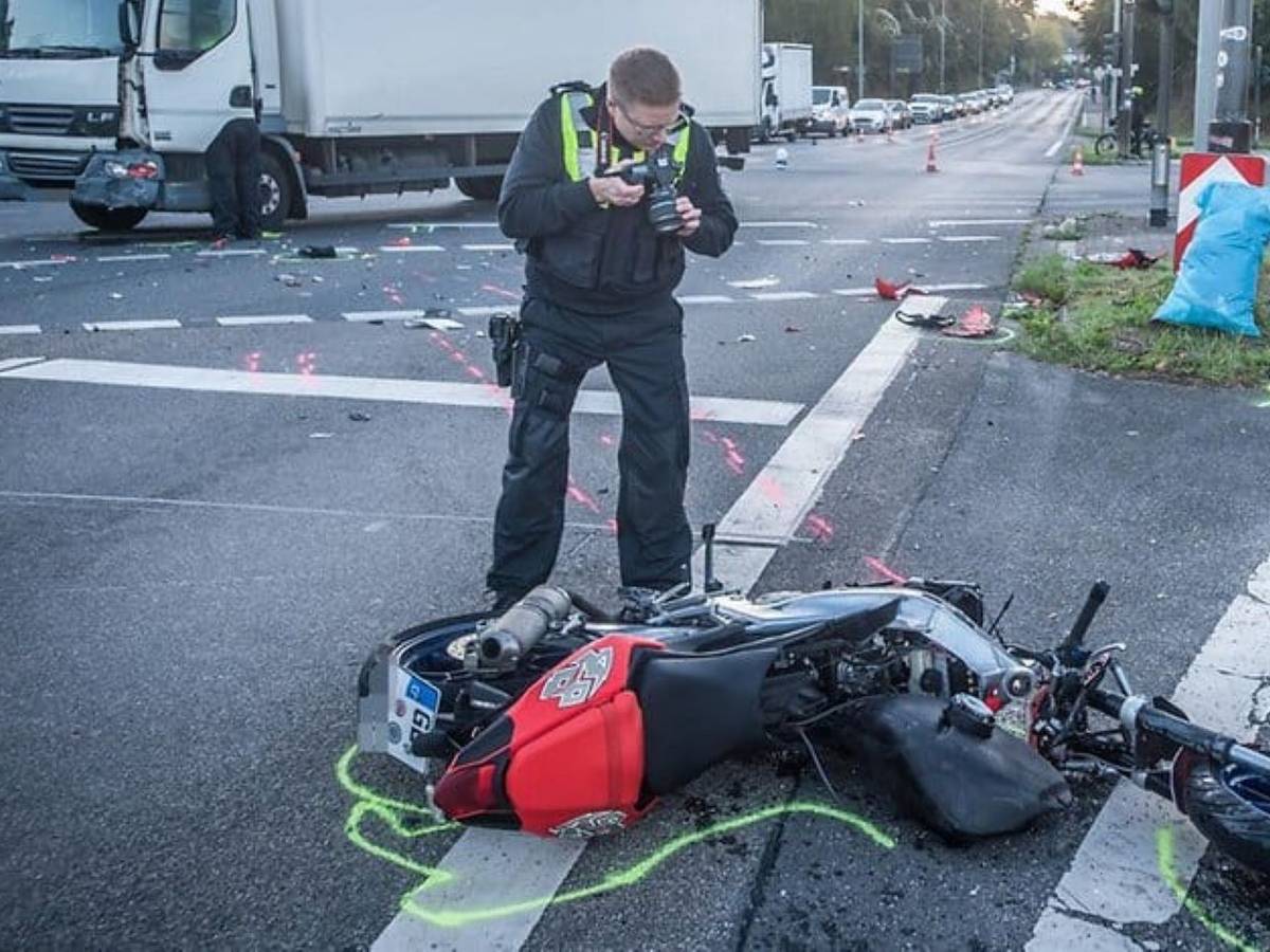Nach einem Unfall in Leverkusen fotografiert ein Polizist das zerstörte Motorrad.