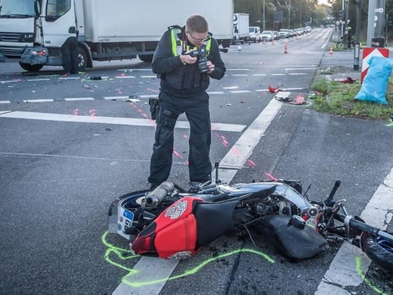 Nach einem Unfall in Leverkusen fotografiert ein Polizist das zerstörte Motorrad.
