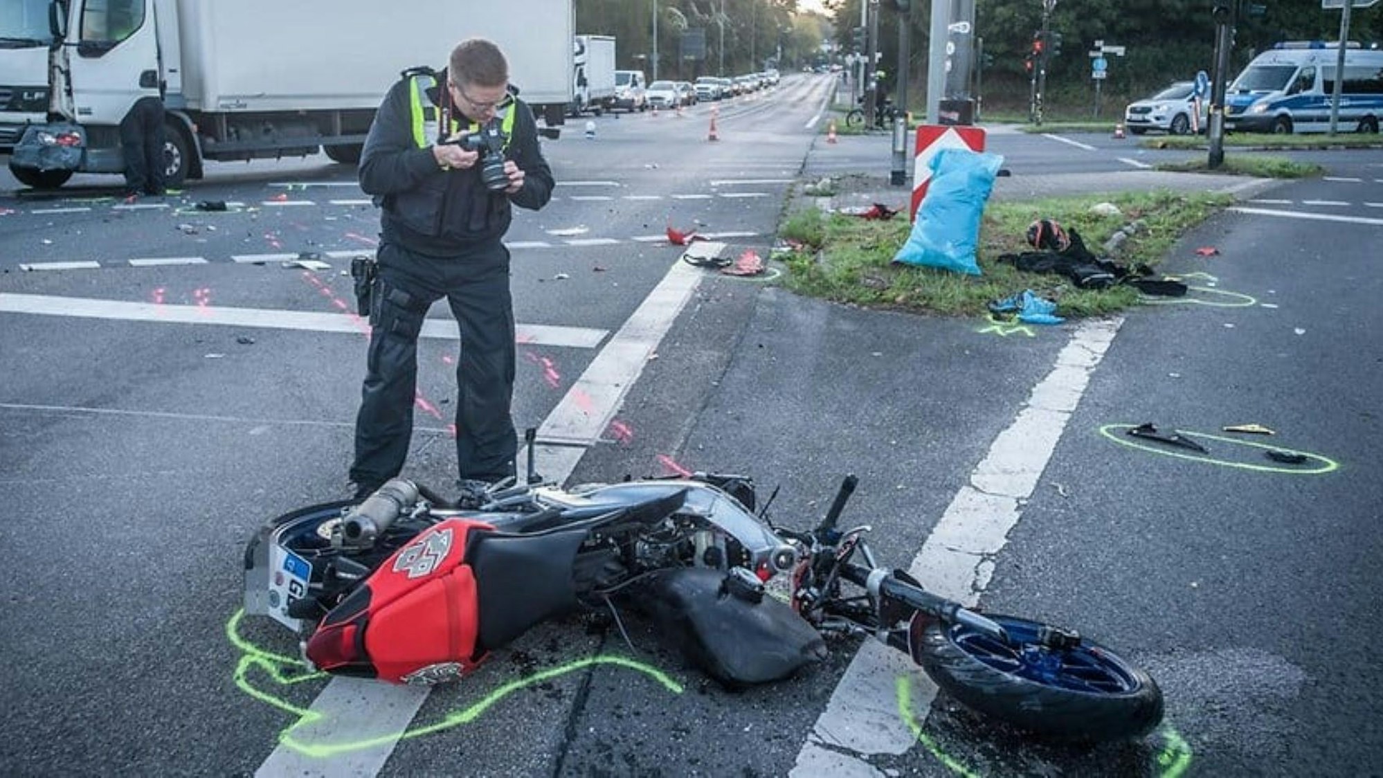 Nach einem Unfall in Leverkusen fotografiert ein Polizist das zerstörte Motorrad.