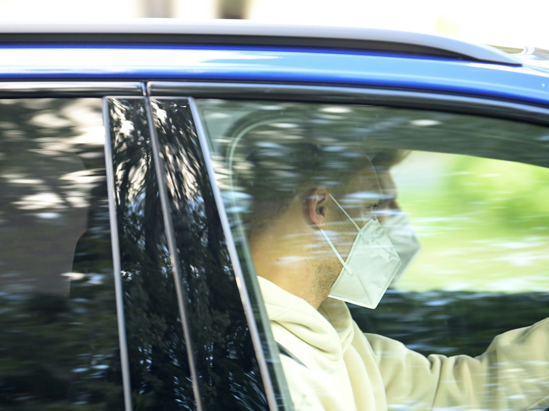 Nationaltorhüter Manuel Neuer sitzt mit Mund-Nasen-Schutz in einem wegfahrenden Auto.