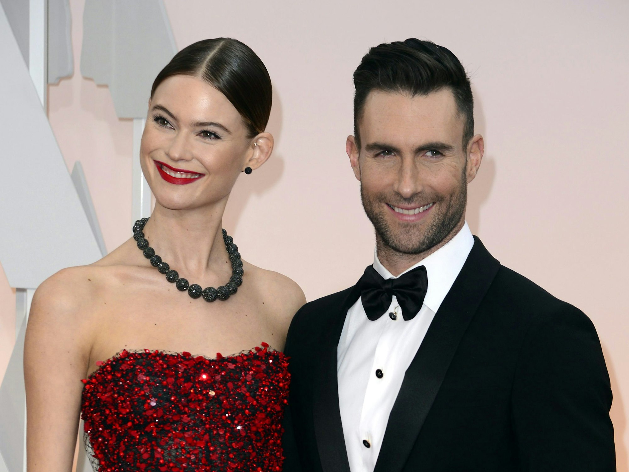 Topmodel Behati Prinsloo erstrahlt in einem roten Pailletten-Dress, während ihr Ehemann Adam Levine sich in einen schwarzen Anzug mit weißem Hemd und Fliege geschmissen hat.