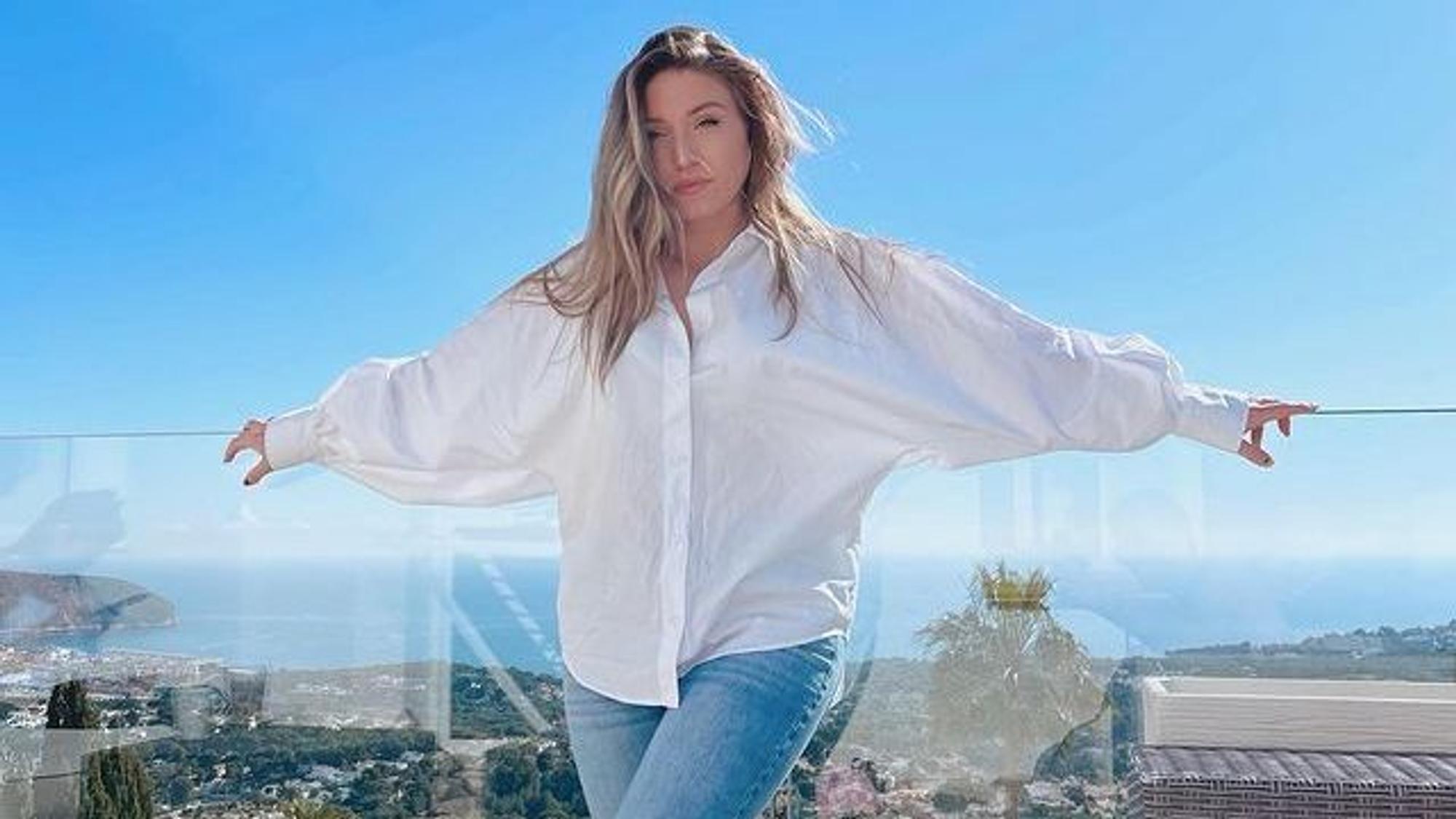 Biancas Noch-Ehemann Julian Claßen verrät im Interview, wie es der YouTuberin, hier auf einem Instagram Foto von Februar 2022, wirklich geht. Auf dem Foto steht Bianca in Jeans und weißer Bluse vor einer Glas-Ballustrade. Im Hintergrund ist das Meer zu sehen.