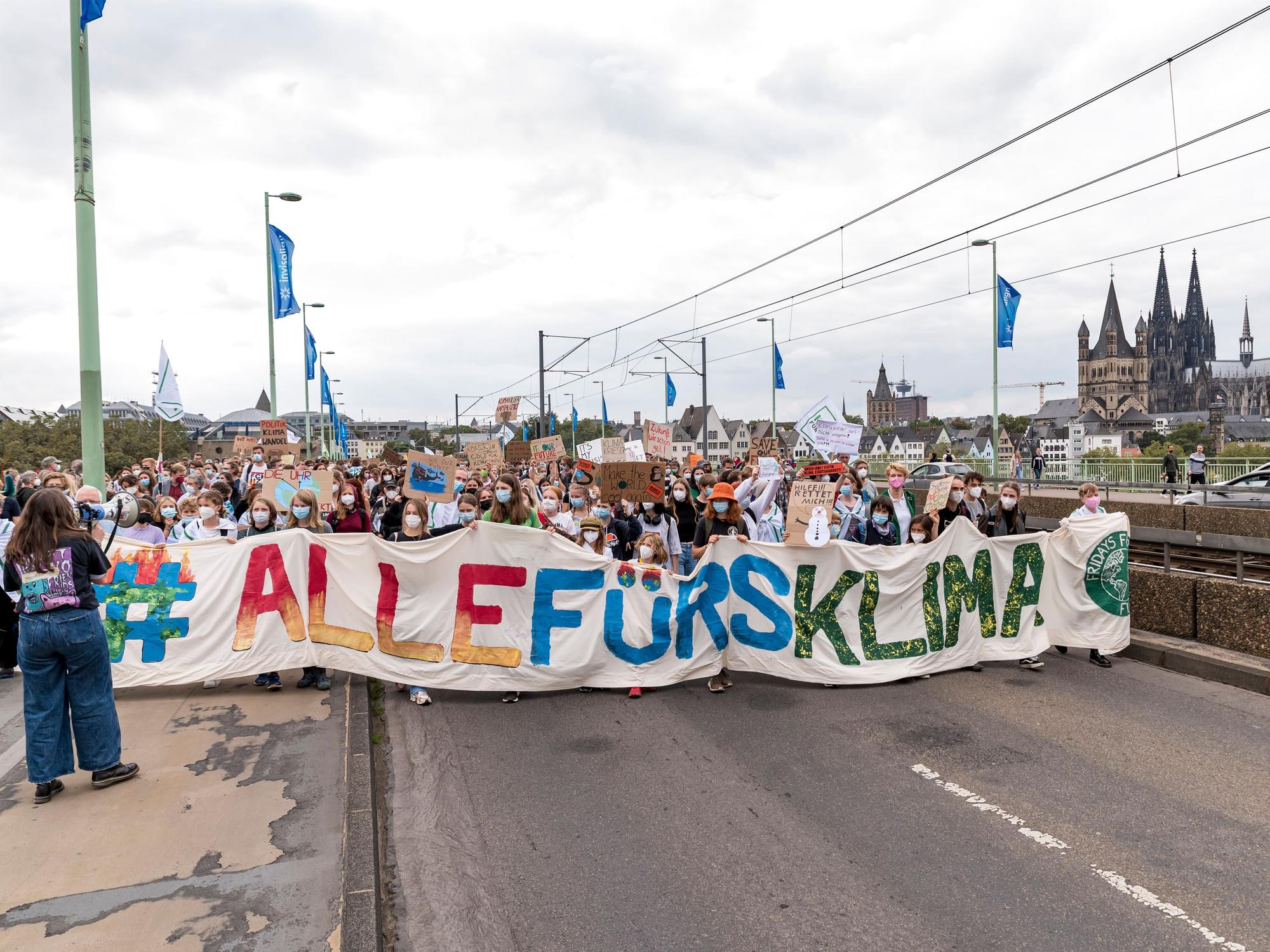 Viele Menschen demonstrieren mit einem Plakat auf der Deutzer Brücke in Köln für Maßnahmen gegen den Klimawandel.