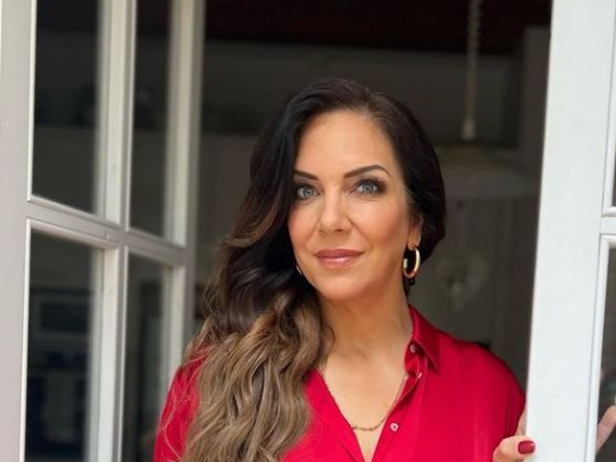 Danni Büchner posiert in einem roten Oberteil an einem Fenster.