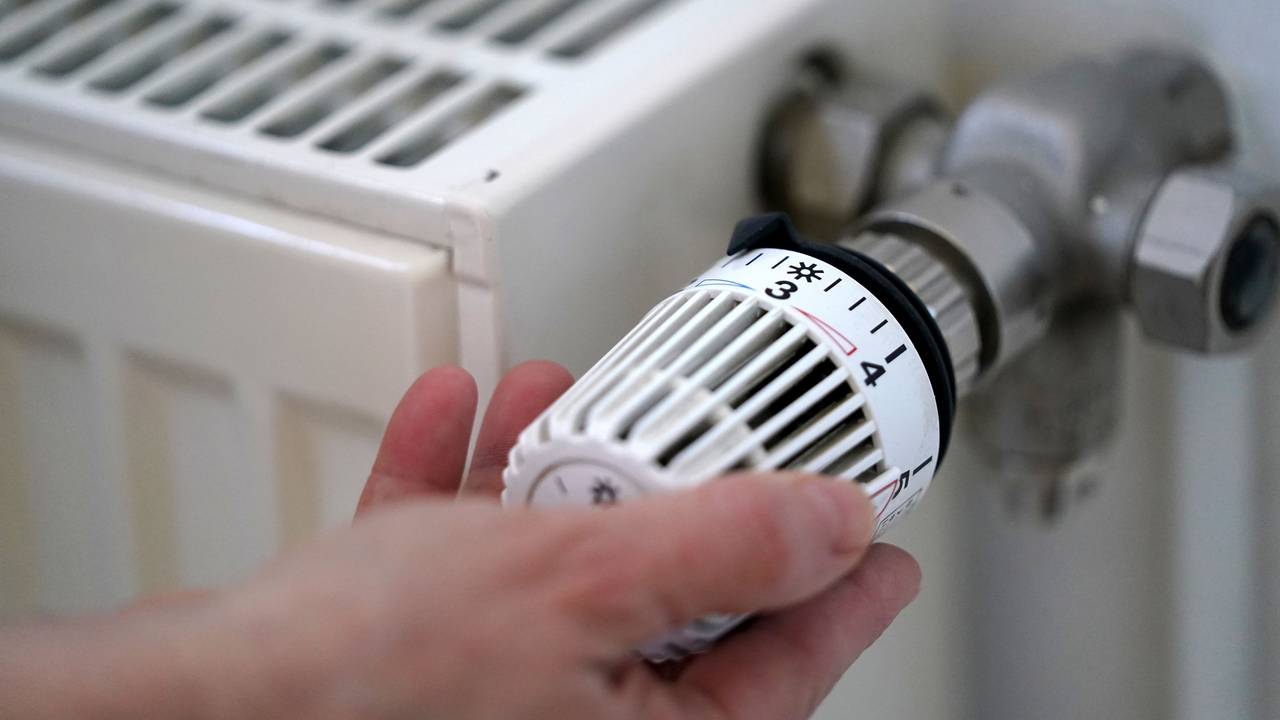 Eine Frau dreht an einem Heizungsthermostat.