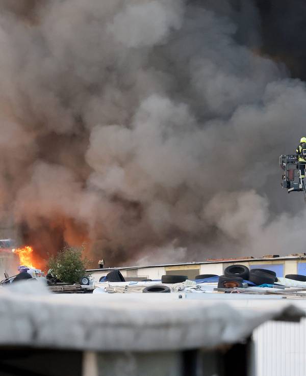 Feuerwehrkräfte bekämpfen von einer Drehleiter einen Brand auf einem Schrottplatz. Ein Brand auf einem Schrottplatz zwischen Neuss und Kaarst hat am Donnerstagabend eine mächtige und weithin sichtbare Rauchsäule erzeugt.