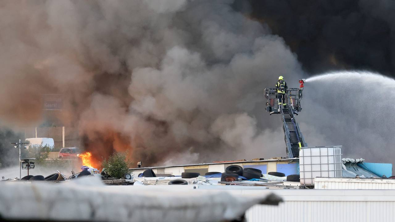 Feuerwehrkräfte bekämpfen von einer Drehleiter einen Brand auf einem Schrottplatz. Ein Brand auf einem Schrottplatz zwischen Neuss und Kaarst hat am Donnerstagabend eine mächtige und weithin sichtbare Rauchsäule erzeugt.