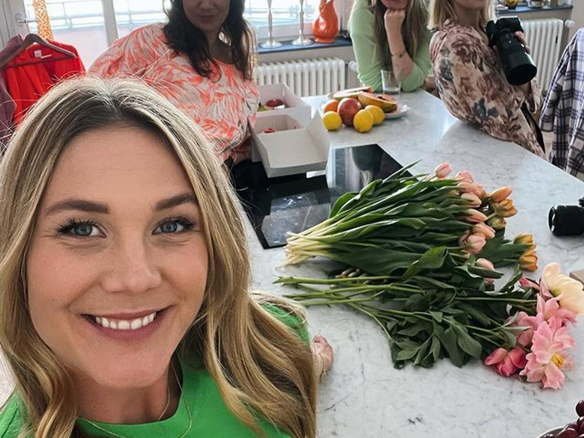 Alina Merkau macht ein Selfie. Im Hintergrund stehen drei weitere Frauen. Hinter ihr auf der Küchenarbeitsplatte liegen verschiedene Blumen.
