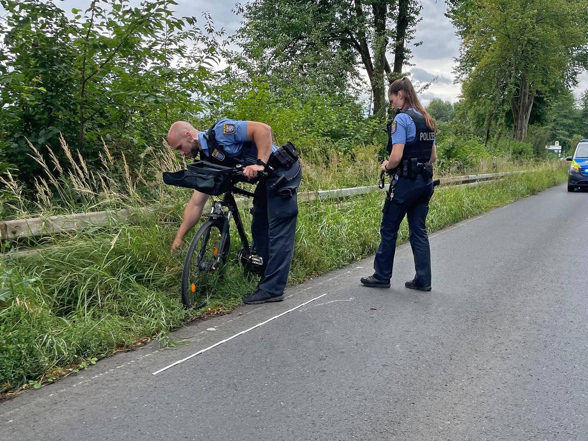 Die Polizistin Milena und der Polizist Dominique inspizieren ein Fahrrad, das in einen Unfall verwickelt ist. Im Hintergrund steht ein Polizeiauto.