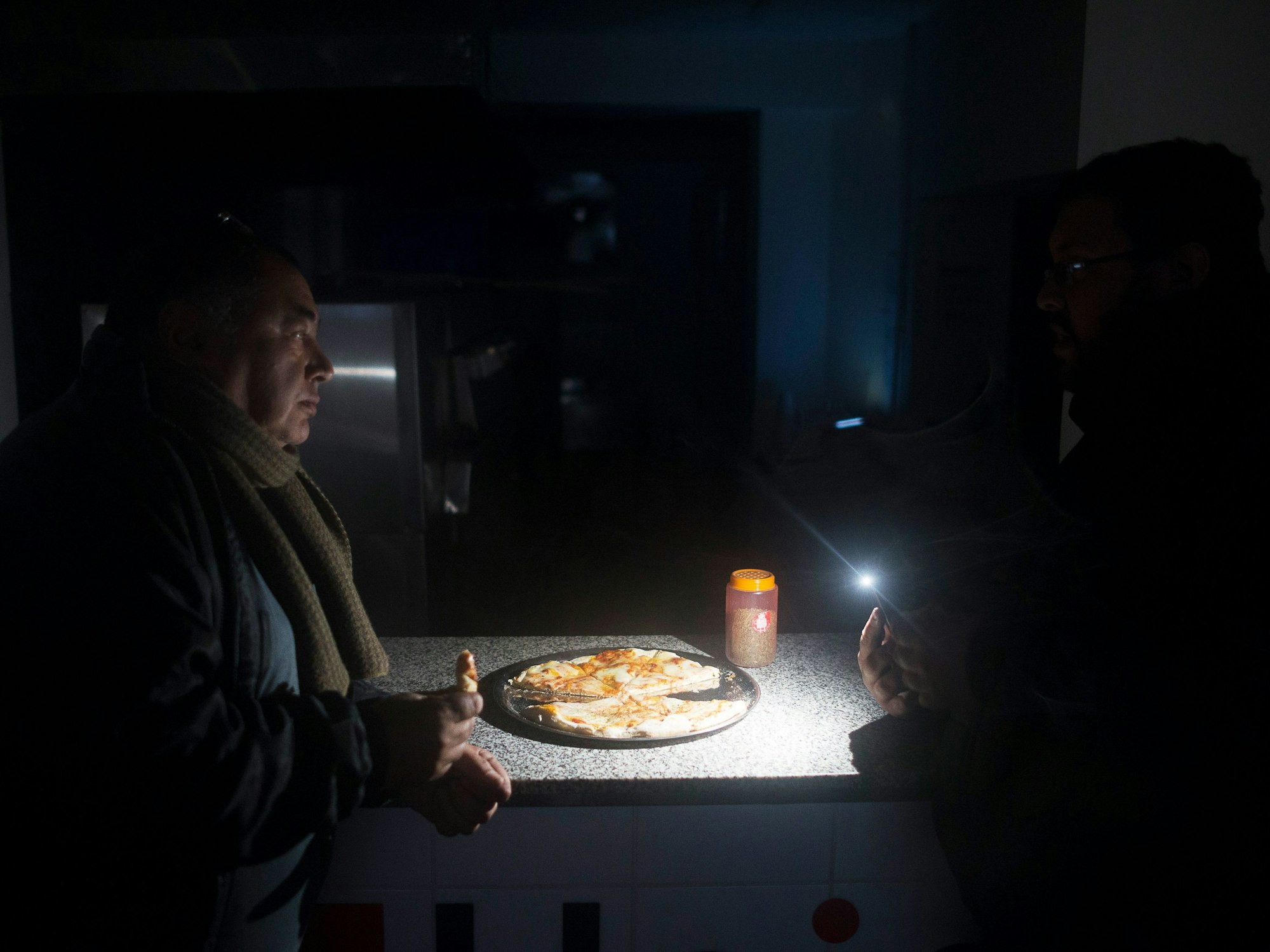 Zwei Männer sitzen in einem Restaurant in Buenos Aires und essen im Schein ihrer Taschenlampen Pizza. Der Stromausfall am 16. Juni 2019 war der größte in der Geschichte des südamerikanischen Landes.