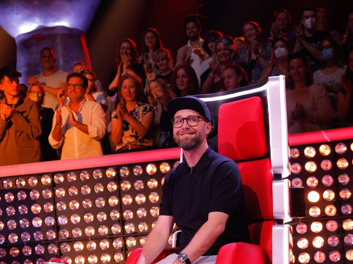 Mark Forster sitzt auf seinem Jury-Stuhl. Er trägt eine helle Hose, ein dunkles Shirt und eine schwarze Kappe.