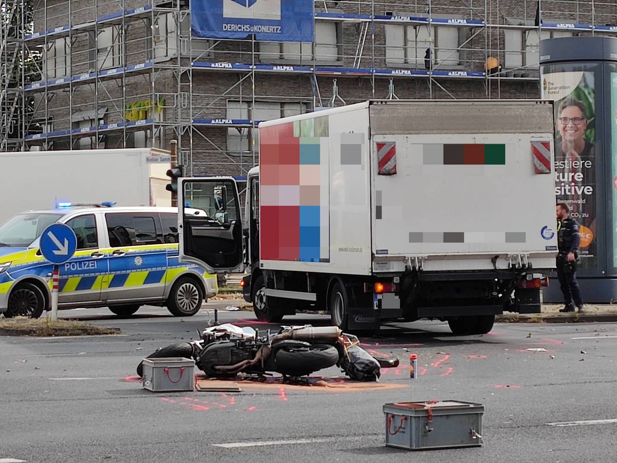 Ein beschädigtes Motorrad liegt auf der Straße, dahinter steht ein Lkw. Ein Streifenwagen sowie mehrere Einsatzkräfte der Polizei sind im Einsatz.