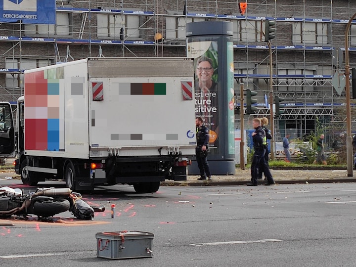 Ein beschädigtes Motorrad liegt auf der Straße, dahinter steht ein Lkw. Ein Streifenwagen sowie mehrere Einsatzkräfte der Polizei sind im Einsatz.
