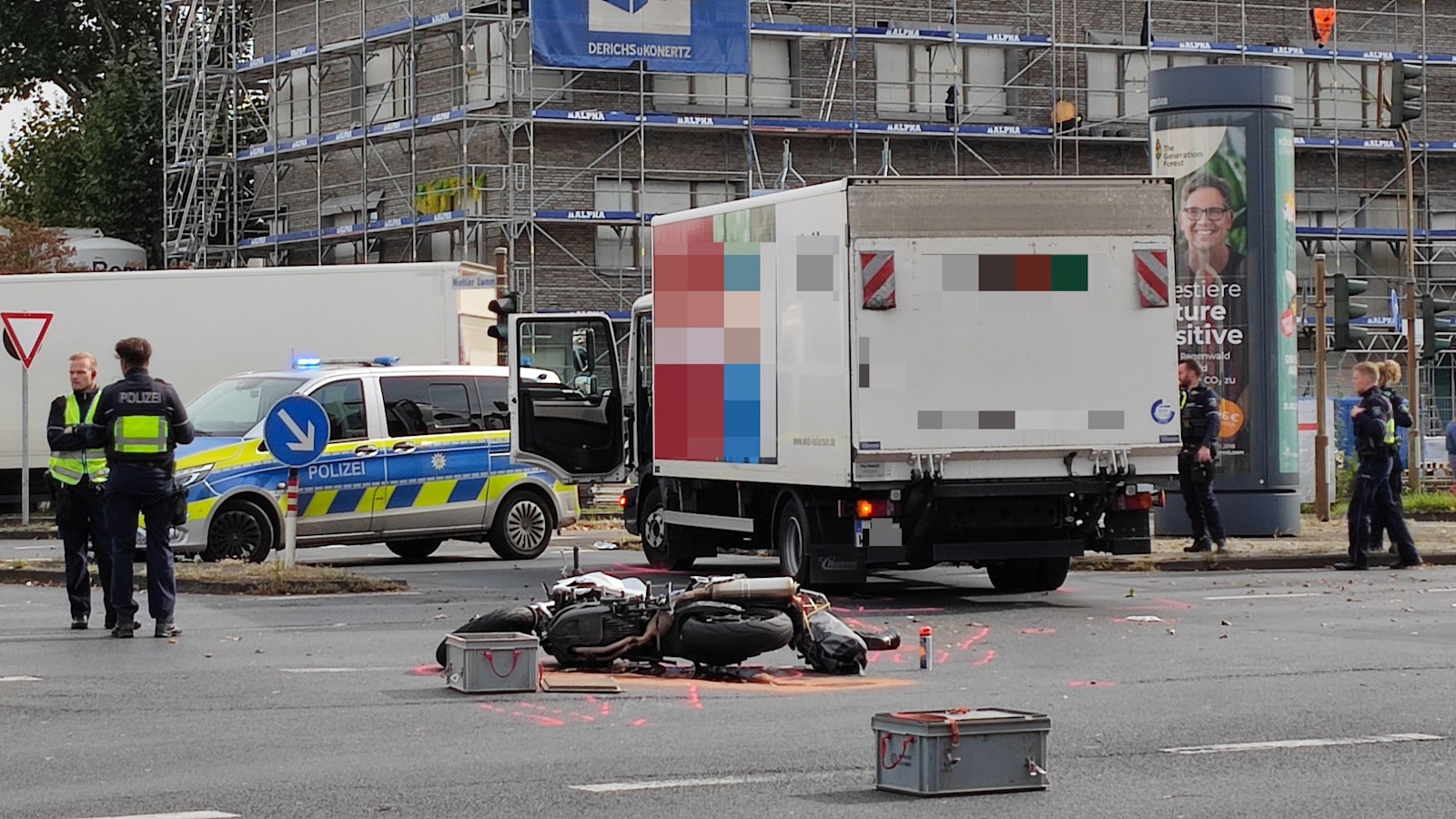 Ein beschädigtes Motorrad liegt auf der Straße, dahinter steht ein Lkw. Ein Streifenwagen sowie mehrere Einsatzkräfte der Polizei sind im Einsatz.