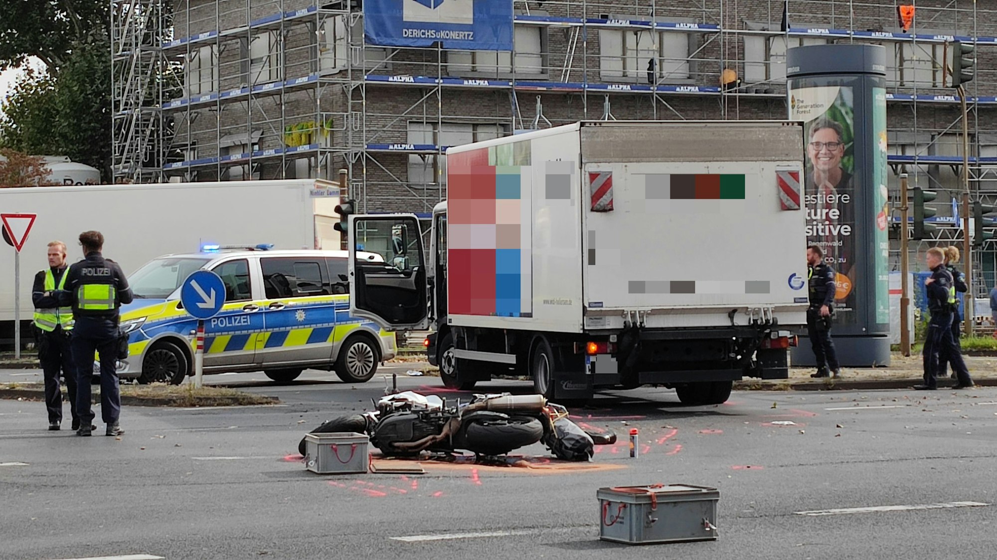 Ein beschädigtes Motorrad liegt auf der Straße, dahinter steht ein Lkw. Ein Streifenwagen sowie mehrere Einsatzkräfte der Polizei sind im Einsatz.