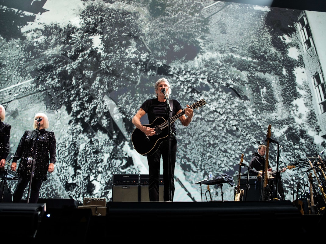 Roger Waters steht mit Gitarre auf der Bühne in Glasgow und singt bei einem Konzert.