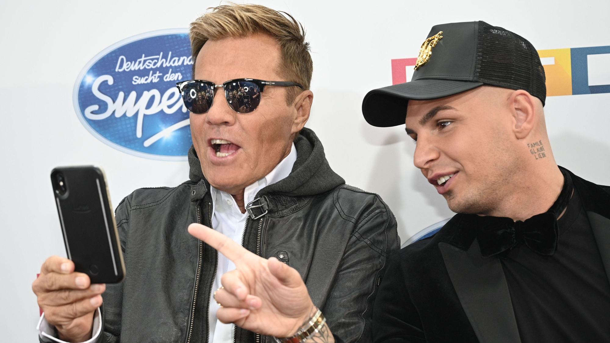 Dieter Bohlen und Pietro Lombardi schauen sich etwas auf einem Handy an.
