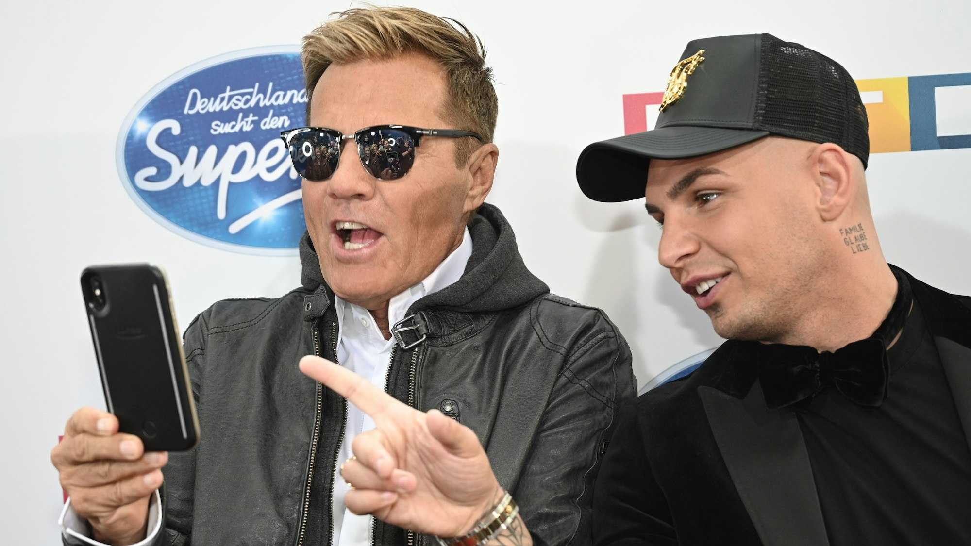 Dieter Bohlen und Pietro Lombardi schauen sich etwas auf einem Handy an.
