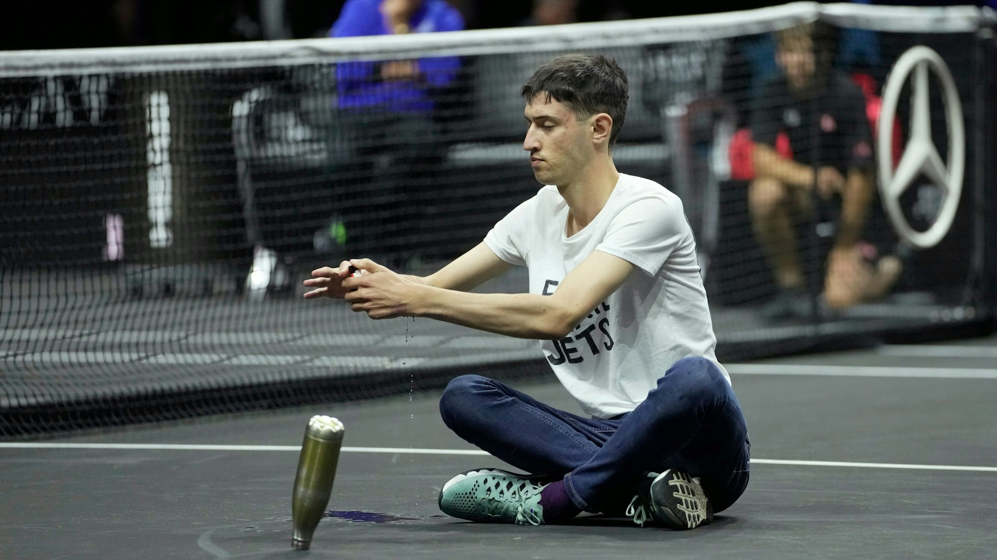 Ein Klimaaktivist sitzt im Schneidersitz auf dem Spielfeld.