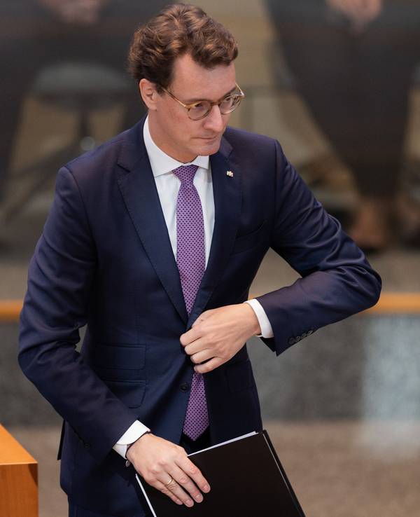 Hendrik Wüst, Ministerpräsident von Nordrhein-Westfalen, geht zum Rednerpult im Plenum des Landtags und knöpft sich dabei das Jackett zu.