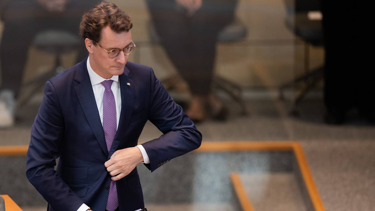 Hendrik Wüst, Ministerpräsident von Nordrhein-Westfalen, geht zum Rednerpult im Plenum des Landtags und knöpft sich dabei das Jackett zu.