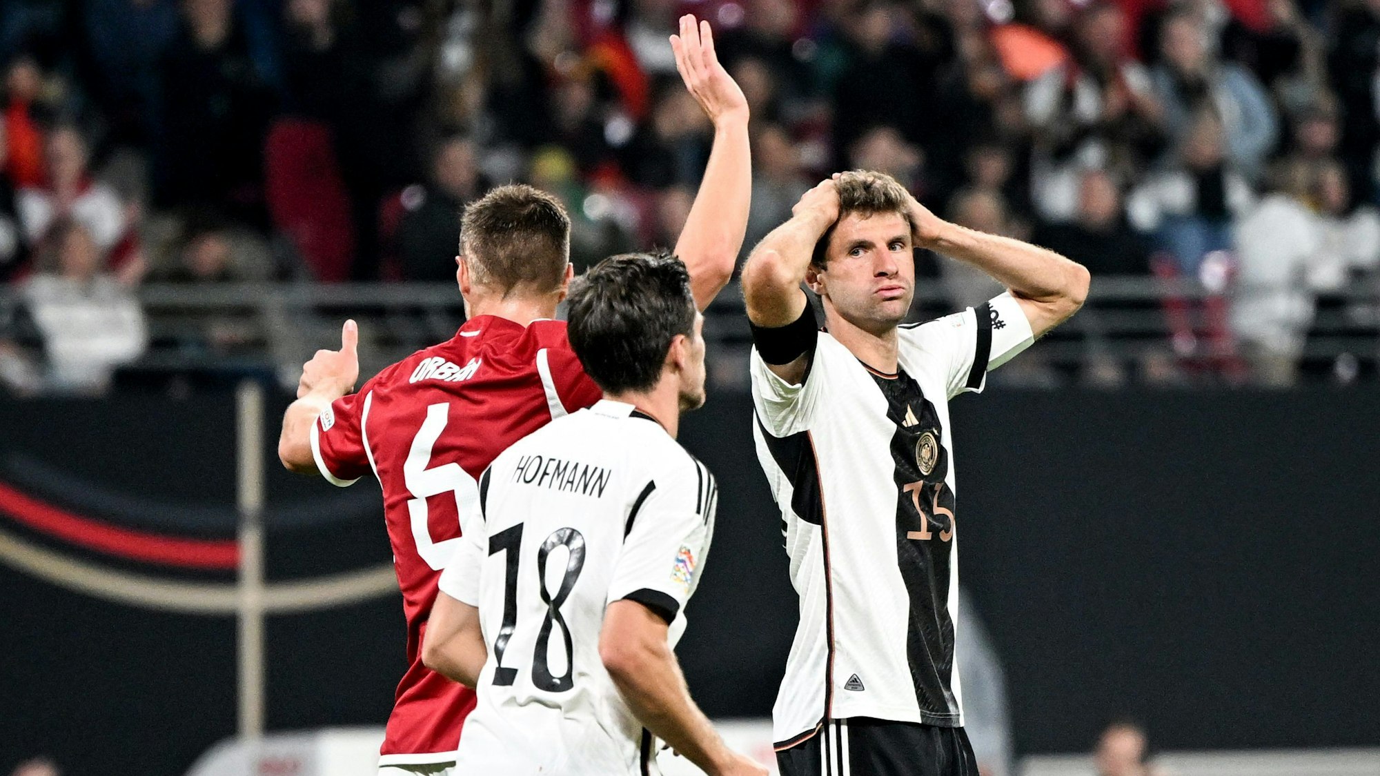 Thomas Müller (r) fasst sich an den Kopf. Neben ihm stehen sein Teamgefährte Jonas Hofmann (M) und Willi Orban von Ungarn.