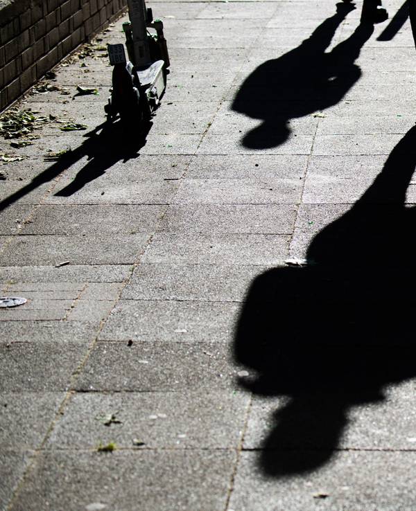 Schüler gehen am Morgen zur Schule und werfen dabei ihre Schatten auf den Gehweg.