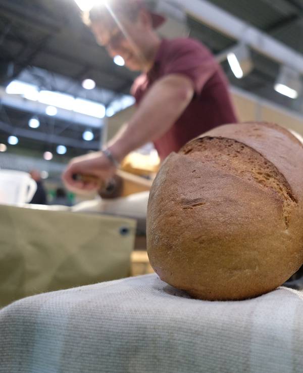 Ein Bäcker zeigt sein Können auf der Messe Agra 2022, während im Vordergrund Brote liegen.