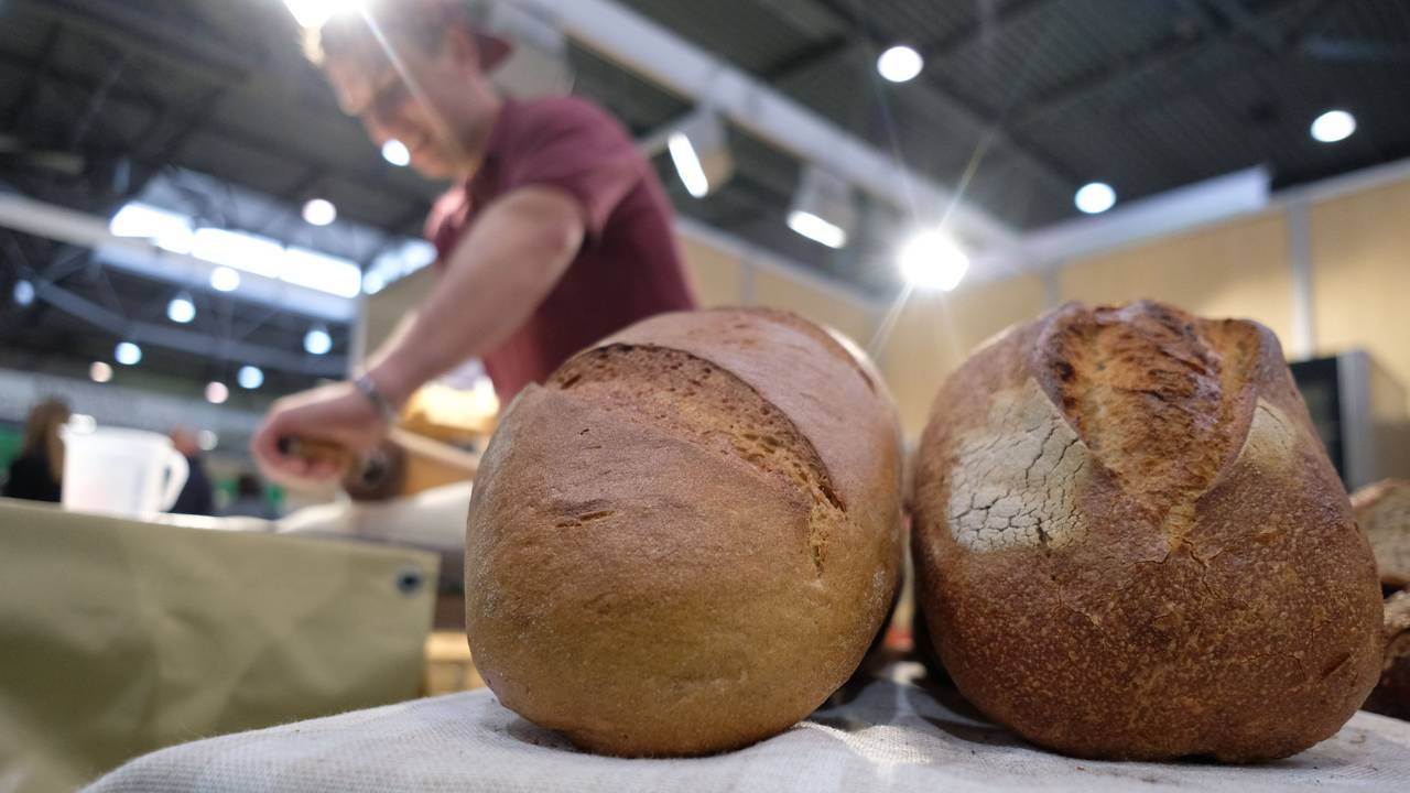 Ein Bäcker zeigt sein Können auf der Messe Agra 2022, während im Vordergrund Brote liegen.