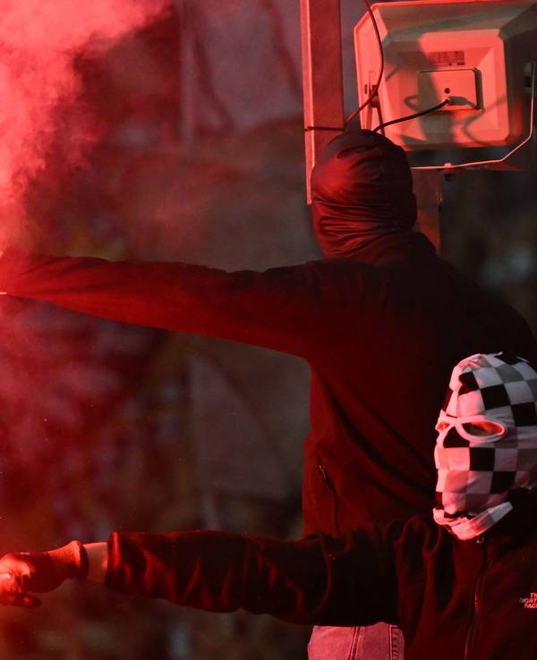 Zwei vermummte Fußballfans zünden Bengalos.