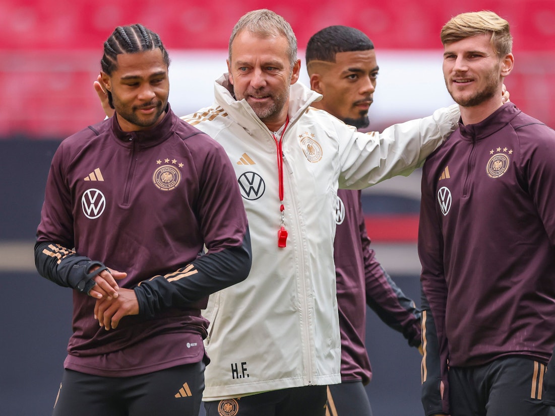 Bundestrainer Hansi Flick (M) und die Spieler Serge Gnabry (l-r), Benjamin Henrichs und Timo Werner stehen während des Trainings im Stadion.