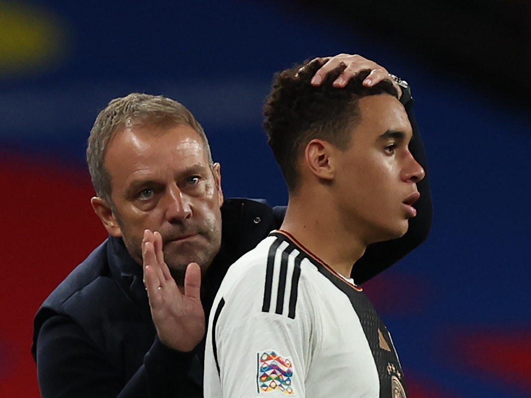 Bundestrainer Hansi Flick tröstet Jamal Musiala während des Spiels.