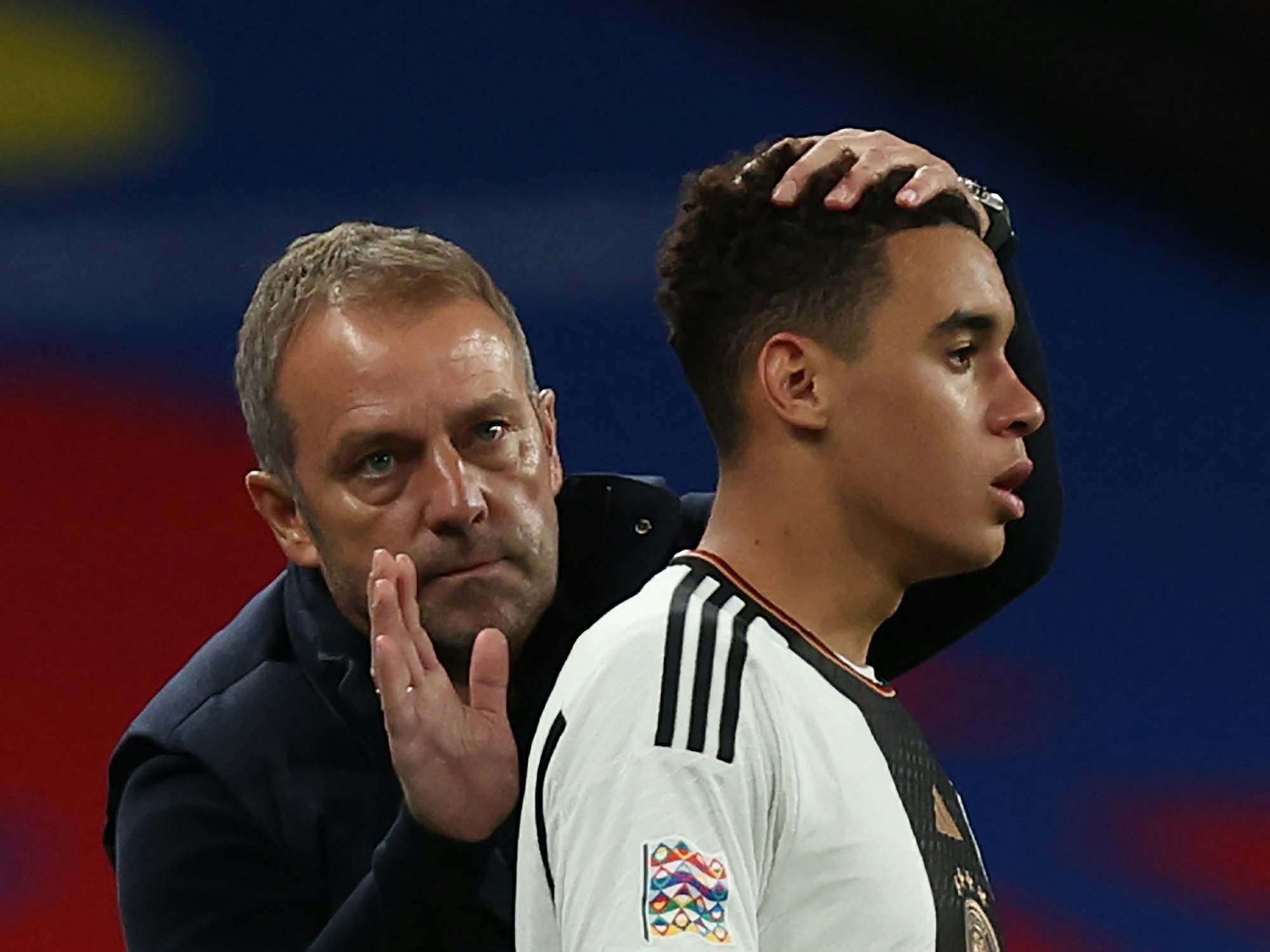 Bundestrainer Hansi Flick tröstet Jamal Musiala während des Spiels.