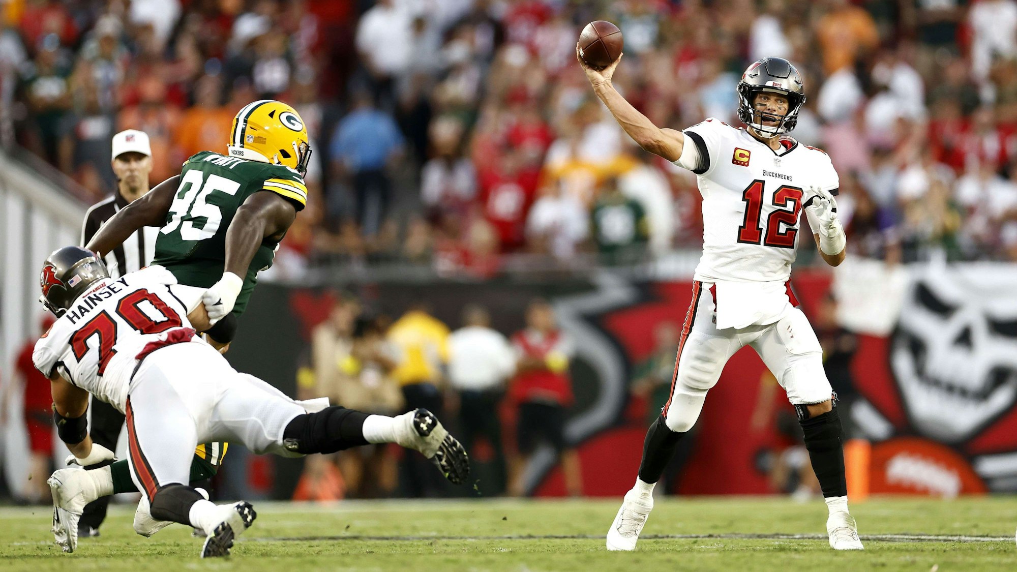 Tom Brady (r.) wirft einen Football, während ein Gegenspieler der Green Bay Packers versucht, ihn daran zu hindern.