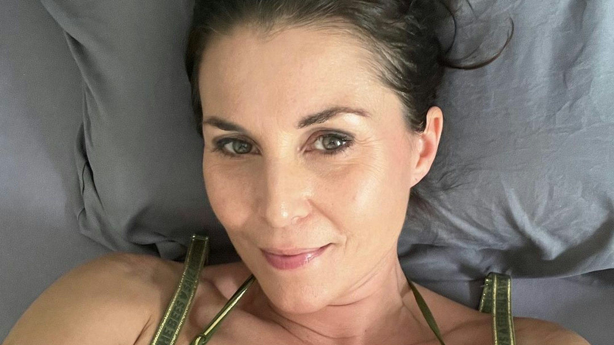 Auf dem Selfie schaut Vanessa in die Kamera. Sie trägt einen dunkelgrünen Bikini mit goldfarbenen Details.