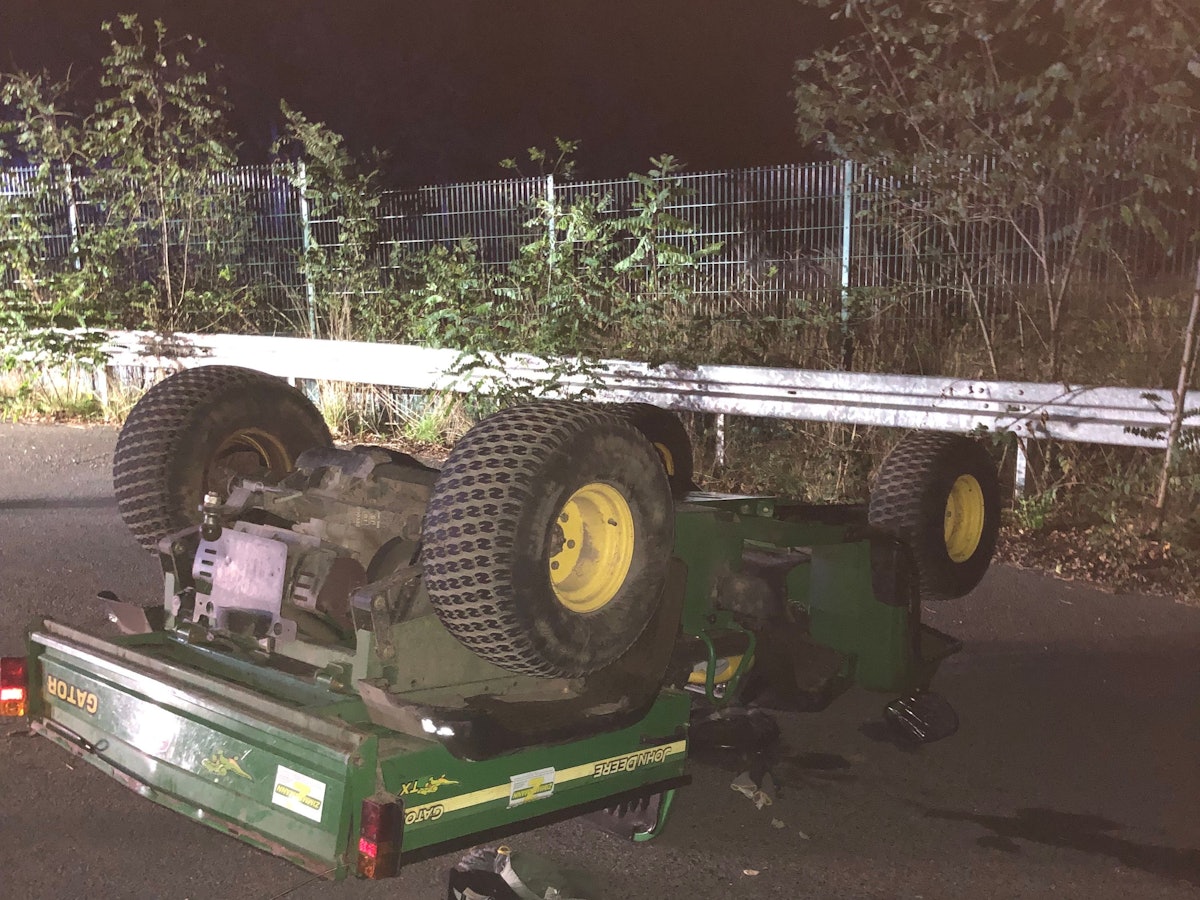 Ein Arbeitsfahrzeug mit offener Ladefläche hat sich überschlagen und liegt mit den Rädern nach oben auf der Straße.