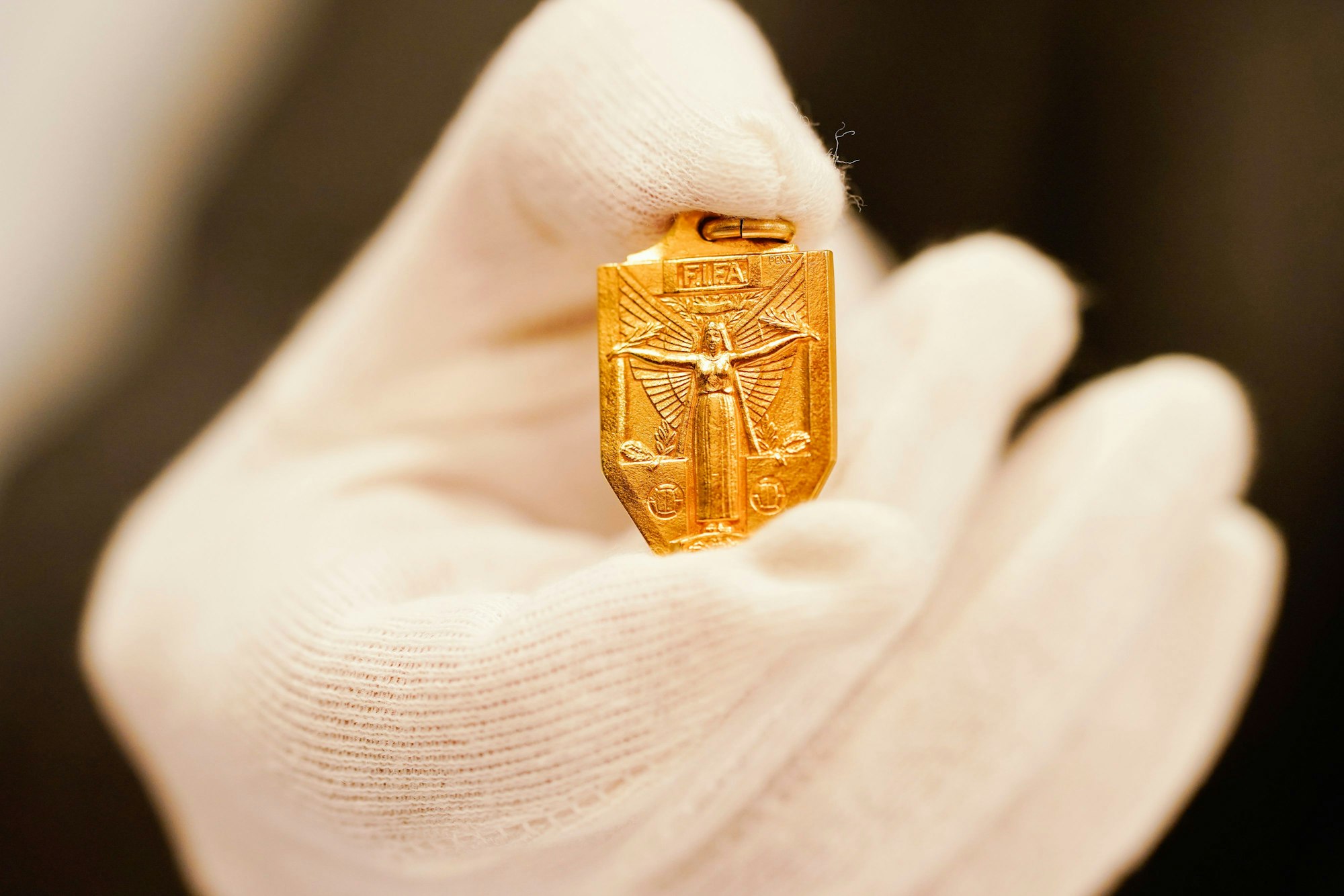 Ein Auktionator hält die Weltmeisterschaftsmedaille von 1954 des verstorbenen Fußballspielers Horst Eckel in den Händen.