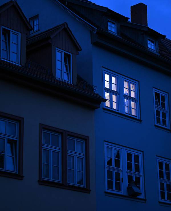 Dieses undatierte Symbolbild zeigt ein hell erleuchtetes Wohnungsfenster im Morgengrauen.